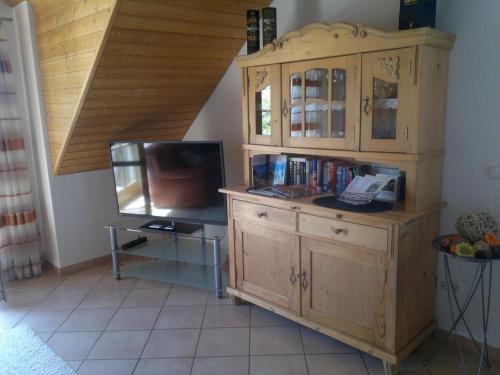 Habitación con TV y armario de madera. en Ferienwohnung Wolfersdorf en Wolfersdorf