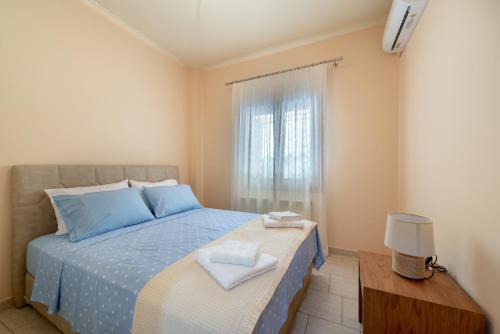 a bedroom with a blue bed and a window at Katerina's Cozy Mountain View Apartment in Argostoli