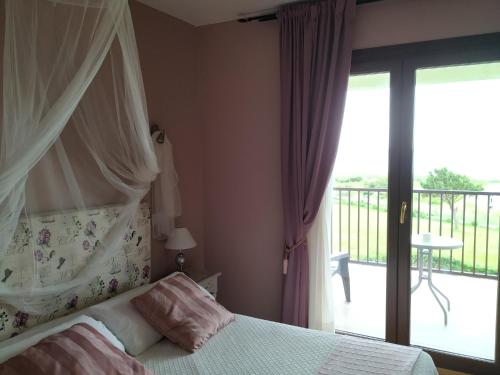 a bedroom with a bed with a canopy and a balcony at El Ribero de Langre in Langre