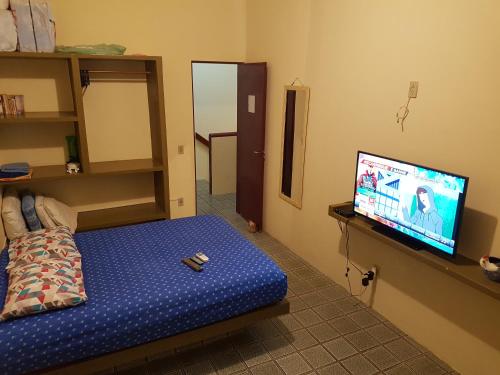uma sala de estar com uma televisão e uma cama com uma almofada em Casa dentro de Porto de Galinhas. 04Suítes.01Quarto. em Porto de Galinhas