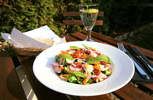 Ein Salat in einer weißen Schüssel auf einem Tisch mit einem Weinglas. in der Unterkunft Malta Premium in Posen