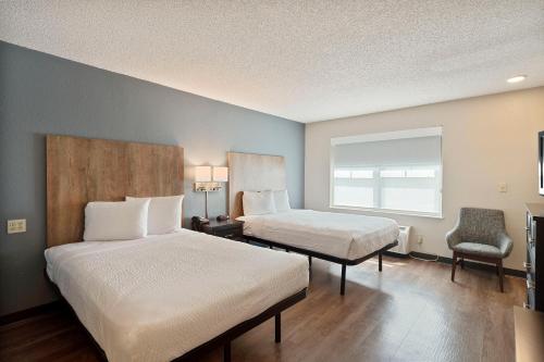 ein Hotelzimmer mit 2 Betten und einem Stuhl in der Unterkunft Extended Stay America Suites - Charlotte - Tyvola Rd in Charlotte