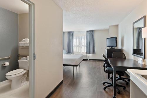 a bathroom with a room with a desk and a bed at Extended Stay America Select Suites - Charlotte - Tyvola Rd in Charlotte