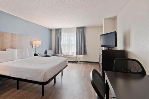 a hotel room with a bed and a flat screen tv at Extended Stay America Select Suites - Charlotte - Tyvola Rd in Charlotte
