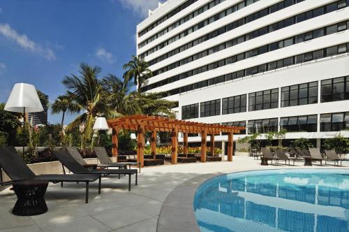 a hotel with a pool and chairs and a building at Hotel da Bahia by Wish in Salvador