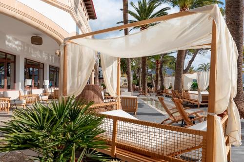 a resort patio with chairs and tables and palm trees at Hoposa Uyal in Port de Pollensa