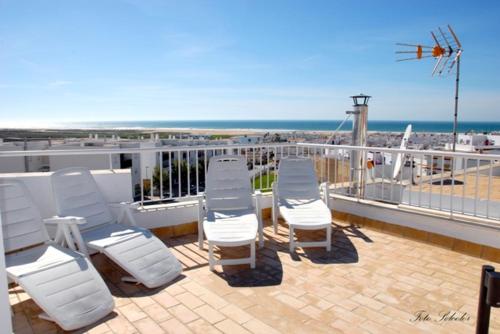 una fila de sillas blancas en un balcón con vistas a la playa en Hostal Al-Andalus, en Conil de la Frontera