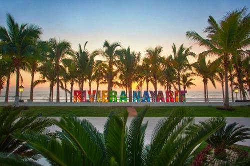 a sign with palm trees in front of the ocean at Occidental Nuevo Vallarta - All Inclusive in Nuevo Vallarta 