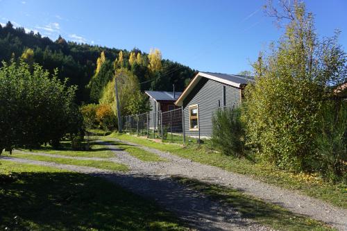 a house on a dirt road next to a forest at Cabañas Cerro Huemules in Coihaique
