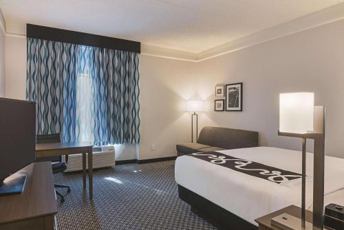 a hotel room with a bed and a desk and a television at La Quinta by Wyndham Orlando UCF in Orlando