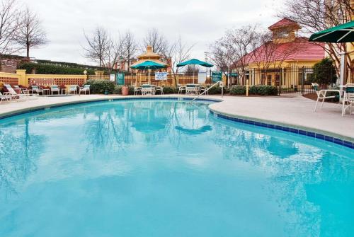 a large blue swimming pool with chairs and umbrellas at La Quinta by Wyndham Haywood Mall-Near Greenville Downtown in Greenville