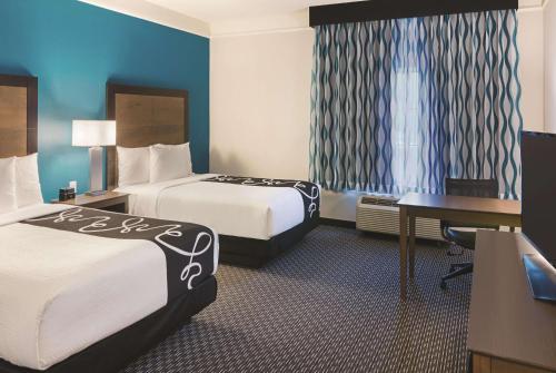 a hotel room with two beds and a desk at La Quinta by Wyndham Orlando UCF in Orlando
