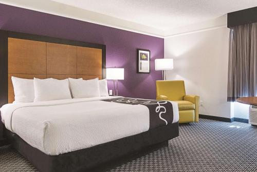 a hotel room with a large bed and a yellow chair at La Quinta Inn & Suites by Wyndham Ontario Airport in Ontario