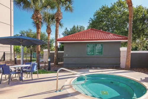 uma pequena piscina com uma mesa e um guarda-sol em La Quinta by Wyndham Orlando UCF em Orlando