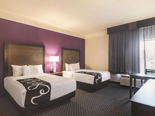 two beds in a hotel room with purple walls at La Quinta by Wyndham Oklahoma City - NW Expwy in Oklahoma City