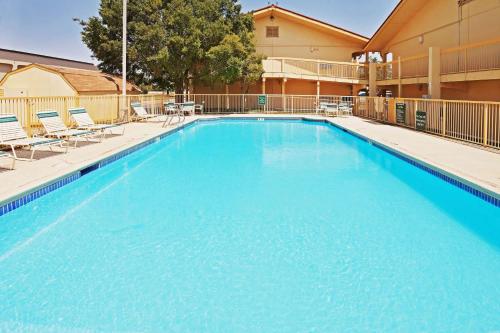 ein großer blauer Pool mit Stühlen und ein Gebäude in der Unterkunft La Quinta Inn by Wyndham Amarillo Mid-City in Amarillo
