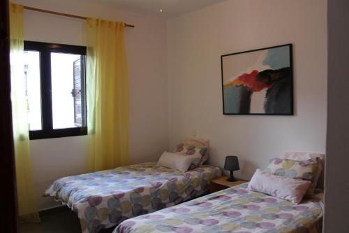 um quarto com duas camas e uma janela com uma fotografia em Apartamento Steffi em Tías