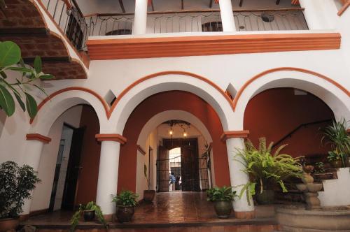 a hallway of a building with arches and potted plants at Hostal Recoleta Sur in Sucre