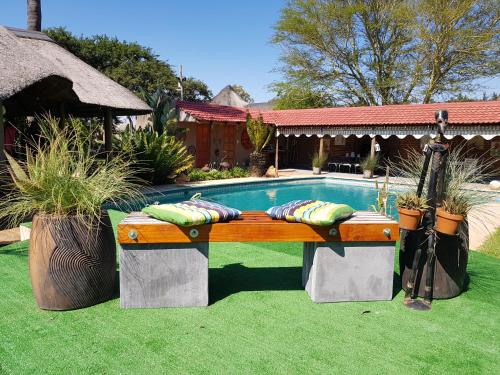 ein Pool mit einer Bank neben einem Haus in der Unterkunft ROCKY ALOE LODGE in Krugersdorp