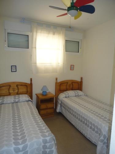 1 Schlafzimmer mit 2 Betten und einem Deckenventilator in der Unterkunft Primera linea de playa Punta del Moral El Espigon in Ayamonte