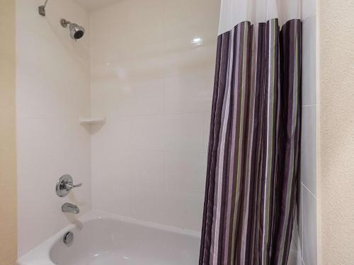 a bathroom with a tub and a shower curtain at La Quinta by Wyndham DFW Airport South / Irving in Irving