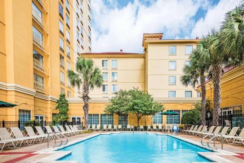 a swimming pool in front of a building with chairs and palm trees at La Quinta Inn & Suites by Wyndham San Antonio Riverwalk in San Antonio
