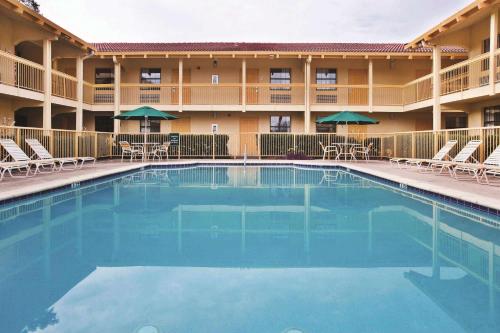 una piscina frente a un hotel con sillas y sombrillas en La Quinta Inn by Wyndham Savannah Midtown en Savannah