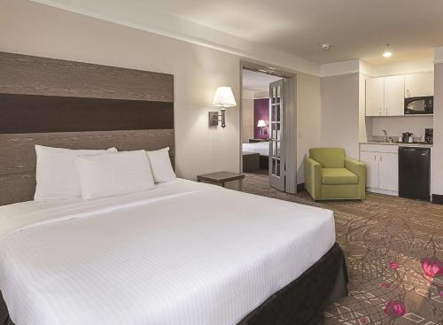 a hotel room with a large bed and a green chair at Kemah Edgewater Hotel, SureStay Collection by Best Western in Seabrook