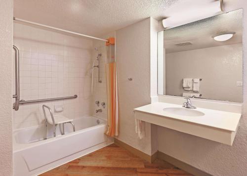 a bathroom with a sink and a tub and a mirror at Travelodge by Wyndham Houston Cy-Fair in Houston