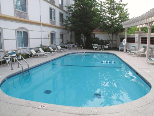 une grande piscine bleue avec des chaises et des tables dans l'établissement La Quinta by Wyndham St. Louis Westport, à Saint-Louis