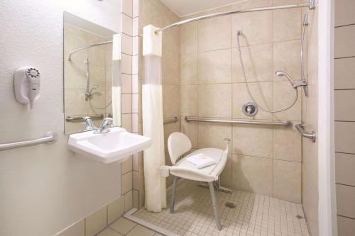 a bathroom with a sink and a shower with a chair at La Quinta by Wyndham Gallup in Gallup