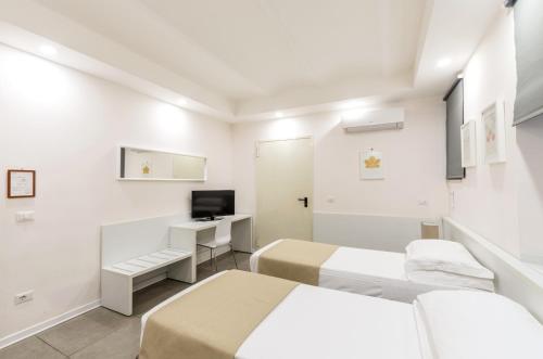 a white room with two beds and a television at Hotel Tempio Di Pallade in Rome