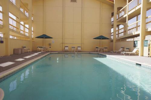 a large swimming pool in a building with tables and umbrellas at La Quinta Inn by Wyndham Albuquerque Airport in Albuquerque