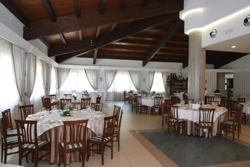 una sala da pranzo con tavoli, sedie e finestre di PARCO DELLE STELLE a Castelmauro