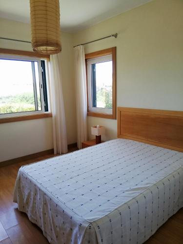a bedroom with a bed in a room with two windows at Moradia São Pedro in Porto Santo
