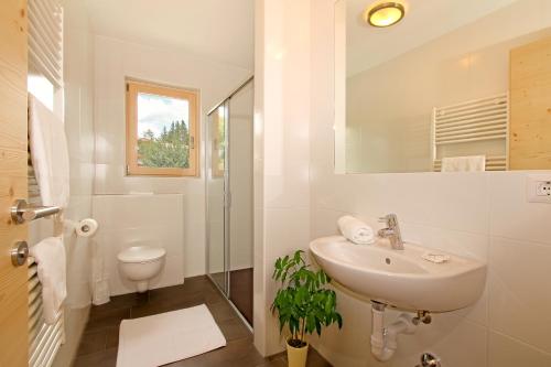 a white bathroom with a sink and a shower at Pension Auerhof in Naz-Sciaves