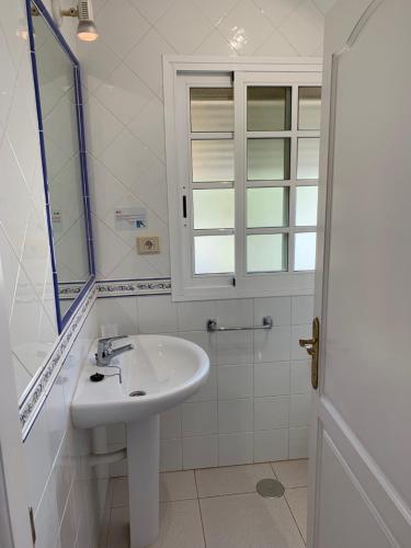 a white bathroom with a sink and a window at Beach Front Villa VV in Corralejo