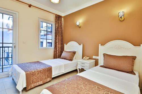two beds in a room with two windows at Enda Boutique Hotel Kalkan in Kalkan