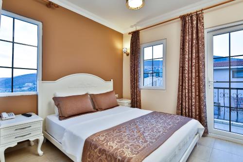 a bedroom with a bed and two windows at Enda Boutique Hotel Kalkan in Kalkan