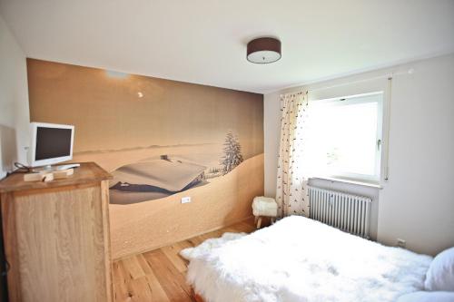 a bedroom with a bed and a desk with a television at Chaletwohnung Seeblick in Oy-Mittelberg