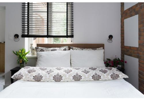 Gostynin Garden Apartment في غوستينين: غرفة نوم بسرير وملاءات بيضاء ونافذة