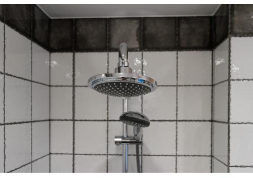 a shower head in a bathroom with white tiles at Gostynin Garden Apartment in Gostynin