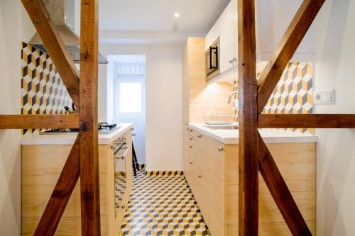 a kitchen with a wooden door with a checkered floor at Bright And Sunny Apartment in Lisbon