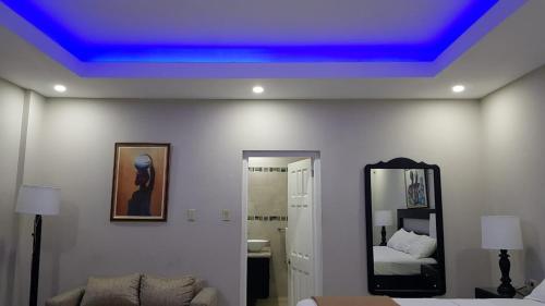 Christar Villas Hotel في كينغستون: غرفة ذات سقف أزرق مع سرير ومرآة