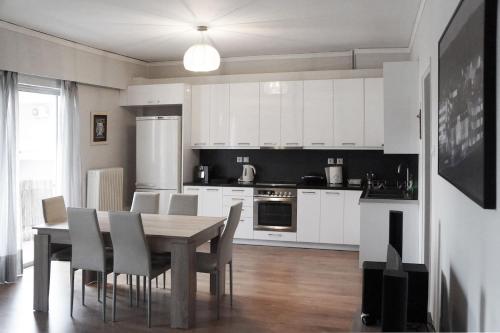 a kitchen with white cabinets and a table and chairs at Comfy Apartment With Acropolis View in Athens