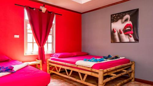 Dos camas en una habitación con paredes rojas. en Sun Beach Bungalows, en Haad Rin