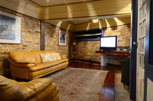 a living room with a couch and a television at Hotel Pousada Casa Grande in Ouro Preto