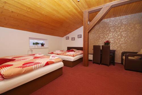a bedroom with two beds and a wooden ceiling at Penzion Severka in Smržovka