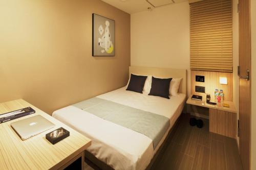 a bedroom with a bed and a desk with a laptop at Hotel UNO Nishikawaguchi Nishiguchi in Kawaguchi