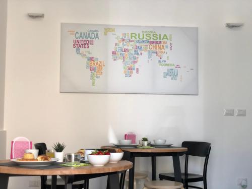 a map of the world on a wall with two tables at Terra di Sicilia Luxury Centro in Avola